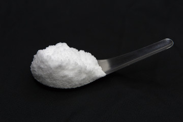 Sea salt in spoon on black background