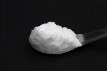 Sea salt in spoon on black background