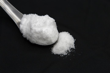 Sea salt in spoon on black background