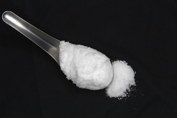 Sea salt in spoon on black background