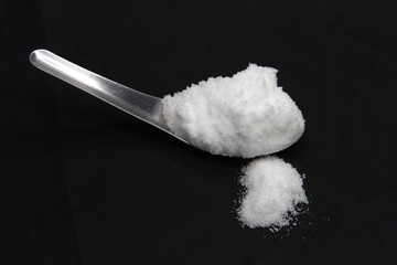 Sea salt in spoon on black background