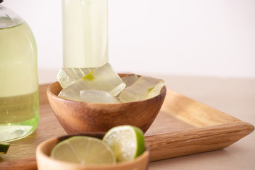 Aloe vera leaf, bowl full of peeled aloe, lemon and bottles of aloe gel or infusion
