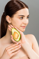 beautiful young woman holding avocado half isolated on grey