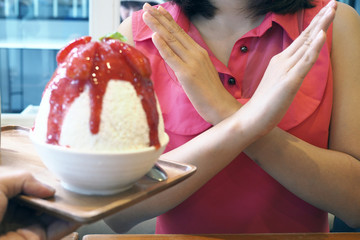 Women push the ice cream cup. Refused to eat all kinds of sweets. Avoid sugar and sweets for good health. diet concept