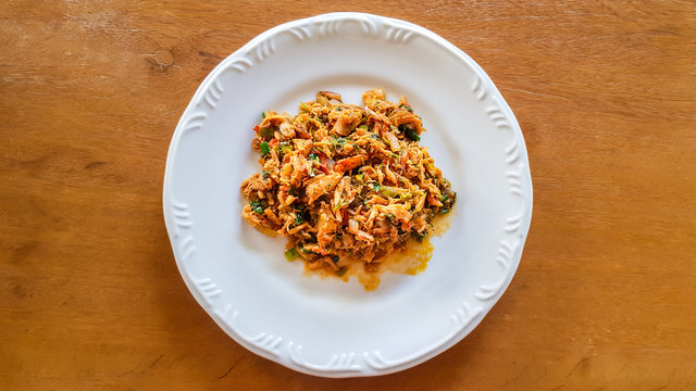 Catado de siri: brazilian food made of crab meat in a white plate on a wooden background