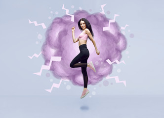 Amazing woman in trendy sportswear jumping. Smiling beautiful slim brunette young girl in fashion leggings and pink top expressing happy emotions. Blue background.