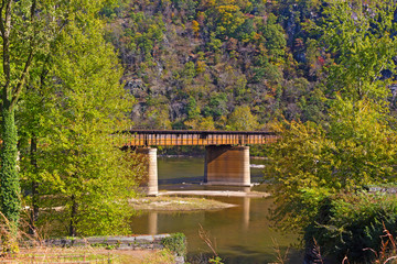 A bridge with railway tracks across Shenandoah River at Harpers Ferry in West Virginia, USA. Autumn in mountains of West Virginia, USA.