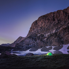 Tente plantée au bord d'un lac de haute montagne par un homme faisant du treckphoto de nuit