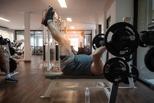  Senior Sportsman Working Out With Barbell At Gym, Elderly Weightlifter Exercising With Heavy Barbell. Aged Fitness Man Doing Deadlift At Sport Studio.