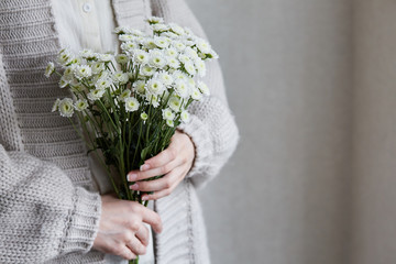 photo of young woman holding white flowers with green stem in her hands - 276646707