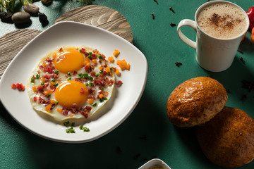 Huevos fritos con tocinera pepino rojo y verde pan y chocolate en fondo verde