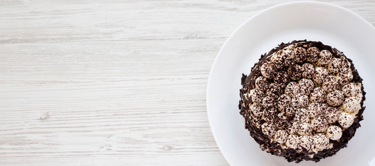 Homemade tiramisu cake on a white plate on a white wooden background, top view. Flat lay, overhead, from above. Copy space.