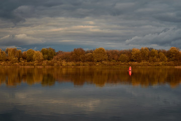 Landscape with views of the river, with a red navigation buoy and overcast skies.
