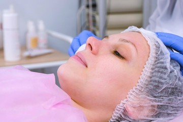 Beautician washes woman's face using cotton pads from mask. Cleaning face