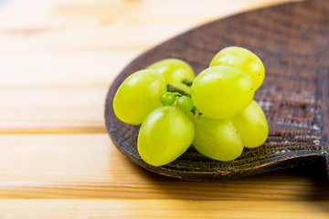 Grapes on a wooden plate . Fruit on the table. Summer harvest on the plate. Green ripe grapes