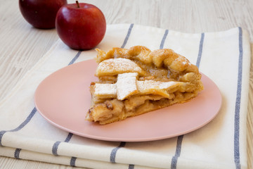 Slice of home-baked apple pie on a pink plate, side view. Closeup.