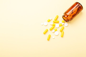 Multicolor tablets and pills capsules from glass bottle on yellow background Heap of assorted various medicine tablets and pills. Health care. Copy space. Top view.