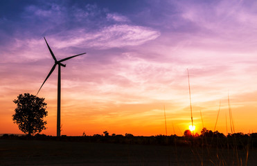 Wind turbines electric power generator on sunset sky at agriculture field