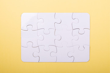 Puzzle pieces on yellow background White puzzle Concept success of business Top view