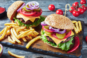 Hamburgers with cheddar cheese on a board