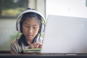 Happy mixed race girl using headphone with smartphone at home.
