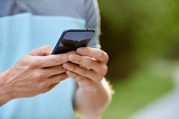 Photo of cellphone in man's hands on green blur background - 276649598