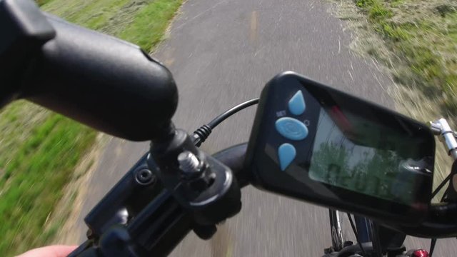 Cyclist checking distance  on the ebike or electric bicycle and pushing button on the e bike controller. Onboard action camera focus on the road. View from first person perspective POV. 4k.
