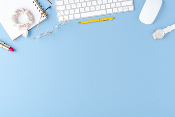 Office desktop with fashion accessories on blue background