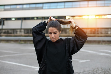 Sporty young woman getting ready before urban outdoor morning workout. Fitness and healthy lifestyle concept.