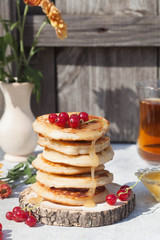 Pancakes with berries, honey and ingredients on the gray and wooden background