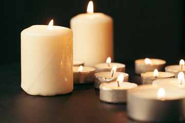 Many candles burning at night. Many candle flames glowing on dark background
