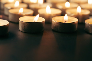 Burning candle on table in darkness, space for text. Funeral symbol
