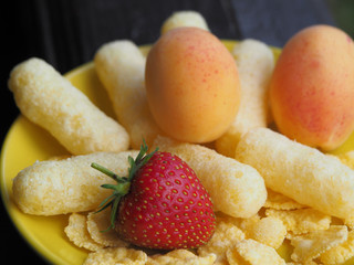 Corn sticks, cereals and fresh fruit are in the yellow plate. Perfect quick Breakfast for kids in the morning.