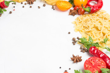 Italian pasta of different kinds with spices, red hot pepper, eggs, yellow and red tomatoes on a white stone background. Concept cooking Italian pasta and sauce