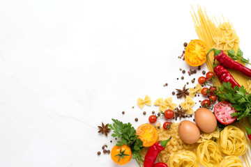 Different types of italian pasta, nests, spaghetti, spices, Red hot chilli pepper, chicken eggs, tomatoes, cherry, light white stone background. Flat lay, top view