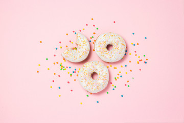Fresh tasty sweet donuts, multicolored decorative candies, sugar cubes on a pink background. Bakery concept, fresh pastries, delicious breakfast, fast food. Flat lay, top view