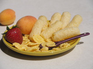 Corn sticks, cereals and fresh fruit are in the yellow plate. Perfect quick Breakfast for kids in the morning.