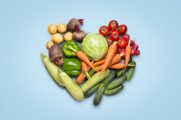 Fresh organic vegetables on a blue background. Concept of buying farm vegetables, care of health, harvest. Heart shape. Country style, Farm Fair. Flat lay, top view