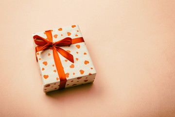 Gift box with red ribbon and heart on coral background, top view with copy space for text