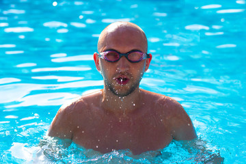 Man in swimming goggles training in blue water swimming pool