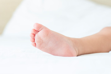 Leg of a sleeping child in bed with white sheets. Concept of a good and sound baby sleep
