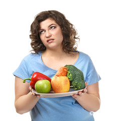 Displeased overweight woman with fruit and vegetables on white background. Weight loss concept