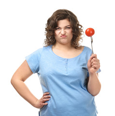 Displeased overweight woman with tomato on white background. Weight loss concept
