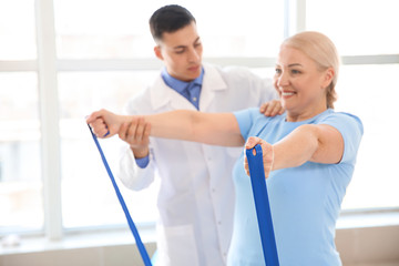 Fototapeta premium Physiotherapist working with mature patient in rehabilitation center