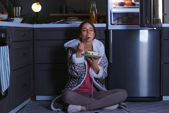 Beautiful Young Woman Eating Unhealthy Food Near Refrigerator At Night