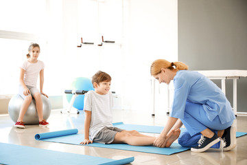 Physiotherapist working with little boy in rehabilitation center