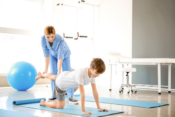 Physiotherapist working with little boy in rehabilitation center