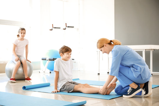 Physiotherapist working with little boy in rehabilitation center