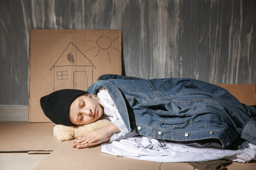 Homeless little girl sleeping on floor near wall