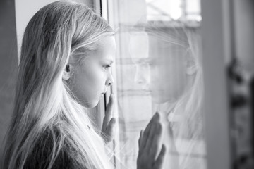 Homeless little girl near window indoors